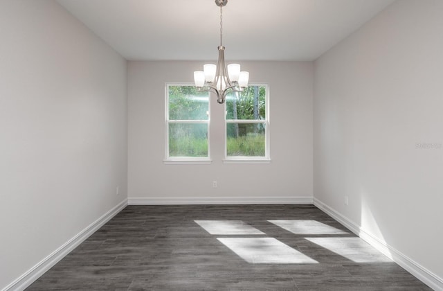 unfurnished room with a notable chandelier and dark hardwood / wood-style flooring