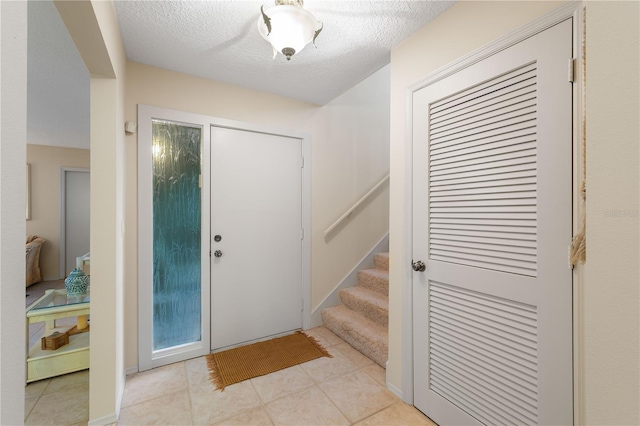 foyer with light tile patterned floors and a textured ceiling