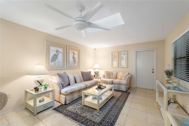 living room with a skylight, ceiling fan, and light tile patterned flooring