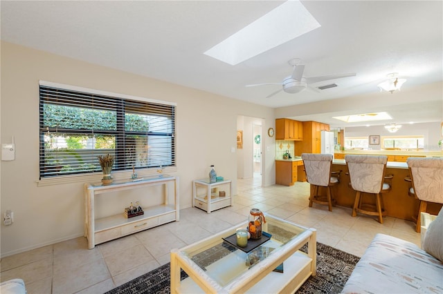 tiled living room featuring a skylight and ceiling fan