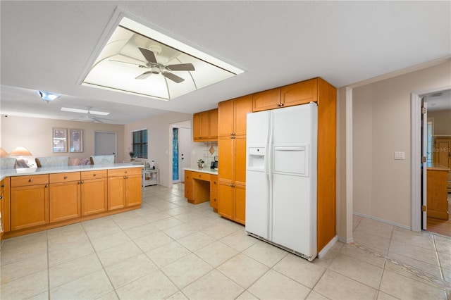 kitchen with kitchen peninsula, ceiling fan, white fridge with ice dispenser, and light tile patterned floors