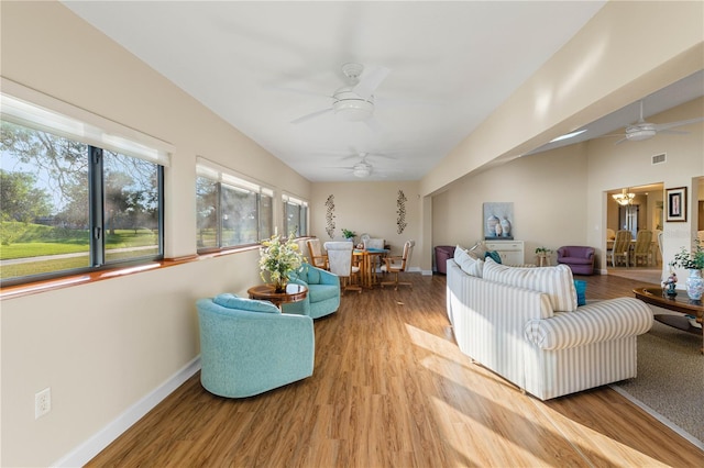 living room with ceiling fan with notable chandelier and light wood-type flooring