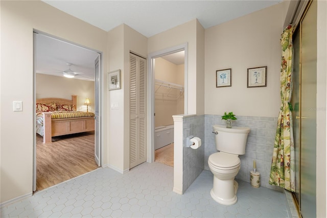 bathroom with hardwood / wood-style flooring, ceiling fan, toilet, and tile walls