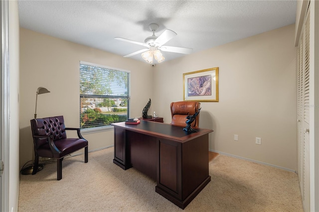 carpeted office space featuring ceiling fan and a textured ceiling