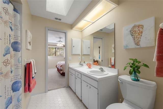 bathroom featuring tile patterned flooring, vanity, a skylight, and toilet