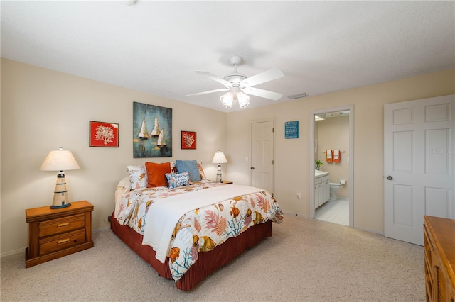 bedroom with light carpet, ensuite bathroom, and ceiling fan