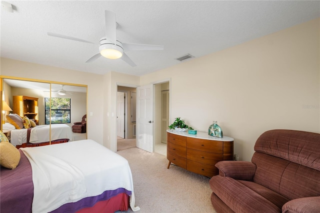 carpeted bedroom featuring ceiling fan, a closet, and a textured ceiling