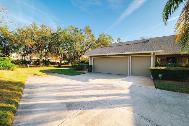 3401 Avenida Madera Unit B, Bradenton, FL 34210 - view of side of home featuring driveway, a garage, a lawn, and roof with shingles