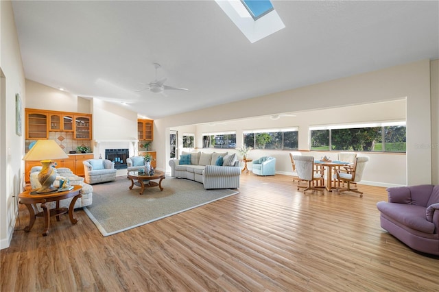 3401 Avenida Madera Unit B, Bradenton, FL 34210 - living room with a glass covered fireplace, a ceiling fan, light wood-style flooring, baseboards, and high vaulted ceiling