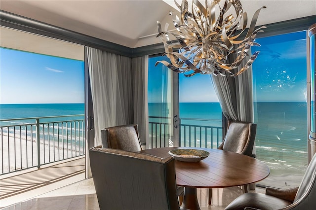 dining area featuring a water view, an inviting chandelier, a beach view, and lofted ceiling