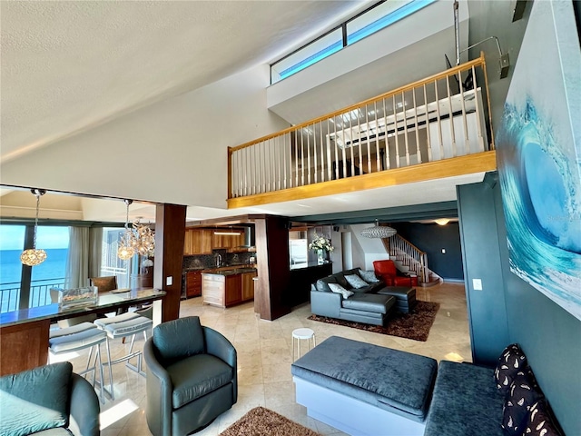 living room featuring light tile patterned floors, a chandelier, a water view, and a high ceiling