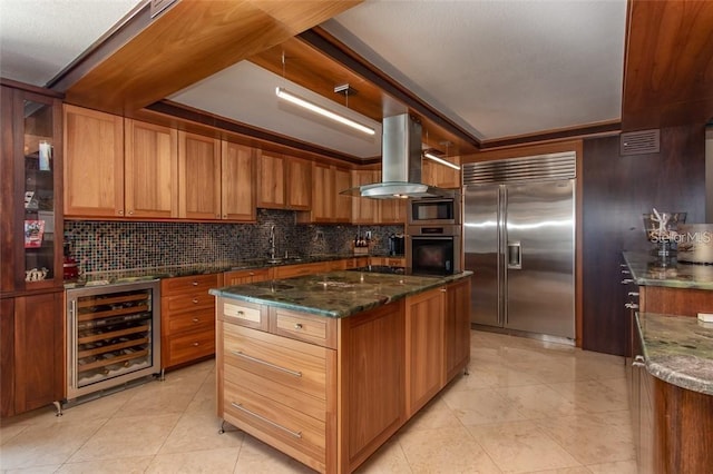 kitchen featuring a center island, dark stone counters, built in appliances, wine cooler, and island range hood