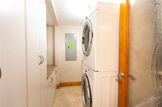 laundry area with cabinets, stacked washer / dryer, and electric panel