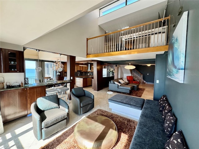 tiled living room with a water view, a notable chandelier, and a towering ceiling