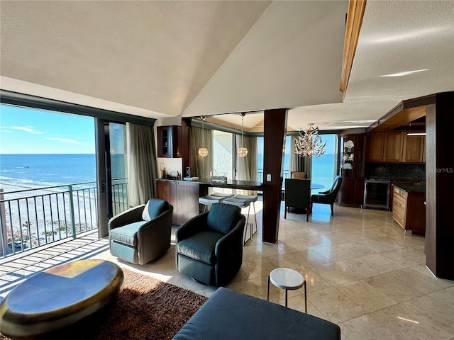 living room featuring a chandelier, lofted ceiling, a water view, and beverage cooler