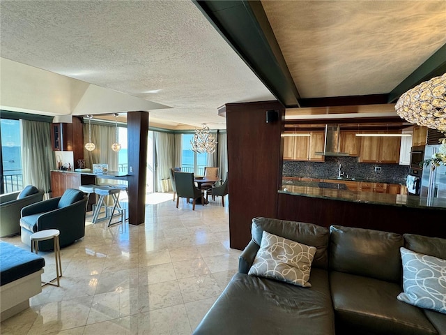 living room featuring a notable chandelier, sink, and a textured ceiling