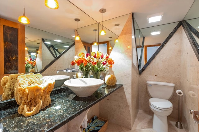 bathroom with toilet, tile walls, tile patterned floors, and sink