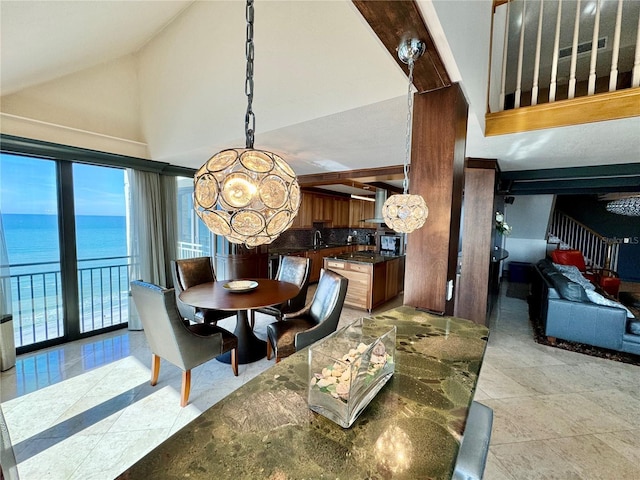 dining area with light tile patterned floors, a chandelier, lofted ceiling, and a water view