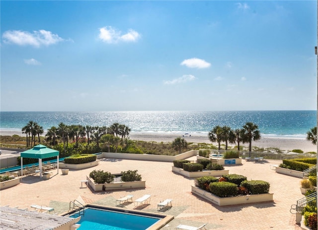 view of pool featuring a view of the beach, a water view, and a patio