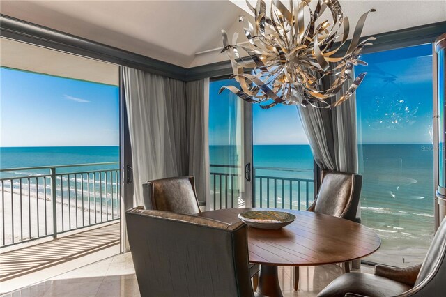 dining area with lofted ceiling, a water view, tile patterned floors, and an inviting chandelier