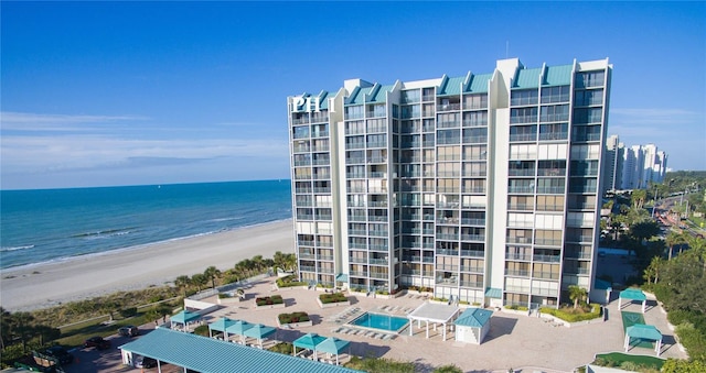 view of building exterior featuring a water view and a beach view