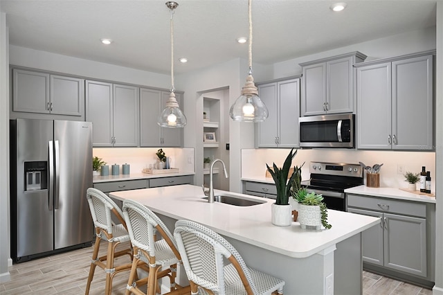 kitchen with appliances with stainless steel finishes, gray cabinets, decorative light fixtures, and sink