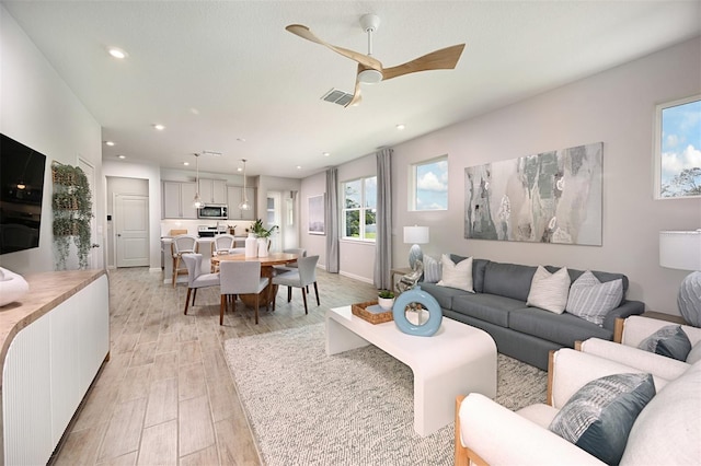 living room with ceiling fan and light hardwood / wood-style flooring