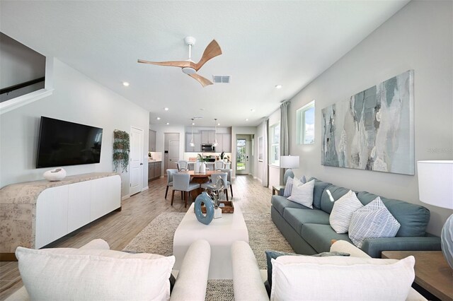 living room with light hardwood / wood-style floors and ceiling fan