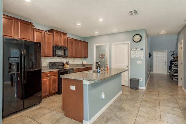 kitchen with sink, an island with sink, a textured ceiling, light tile patterned floors, and black appliances