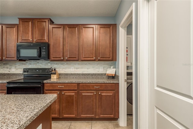 kitchen featuring tasteful backsplash, a textured ceiling, black appliances, light tile patterned floors, and washer / clothes dryer