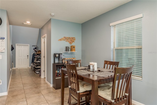 tiled dining space featuring a textured ceiling and vaulted ceiling