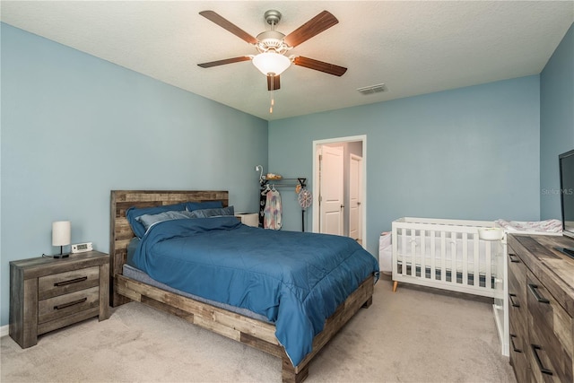 bedroom featuring ceiling fan, light carpet, and a textured ceiling