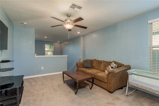 carpeted living room with ceiling fan and a textured ceiling