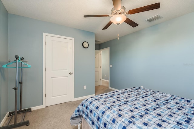 bedroom with a textured ceiling, light colored carpet, and ceiling fan