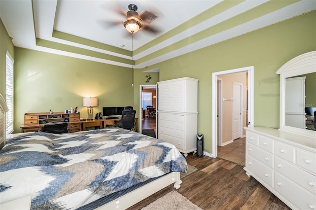 bedroom with dark hardwood / wood-style flooring, a raised ceiling, and ceiling fan