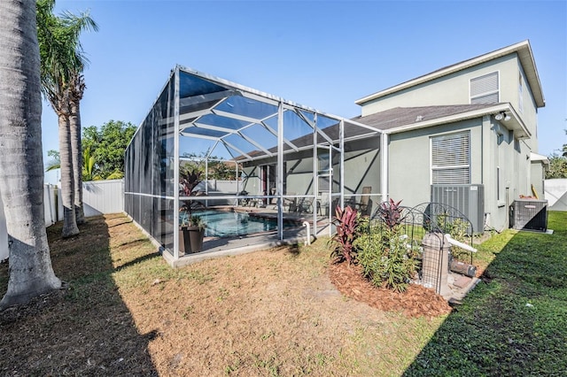 back of property with a lawn, a lanai, and central air condition unit