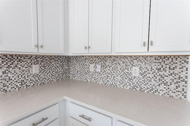 kitchen with tasteful backsplash and white cabinetry