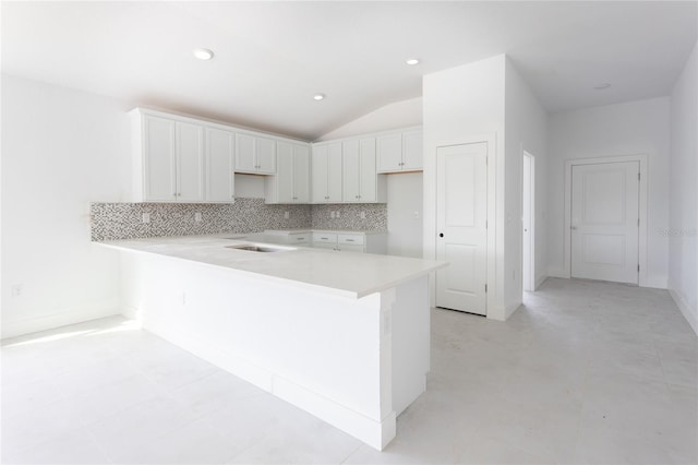 kitchen featuring kitchen peninsula, white cabinetry, vaulted ceiling, and decorative backsplash