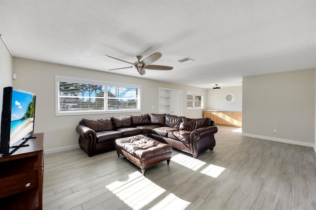 living room featuring a textured ceiling, light hardwood / wood-style flooring, and ceiling fan