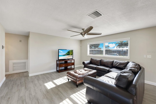 living room with ceiling fan, a textured ceiling, and light hardwood / wood-style flooring