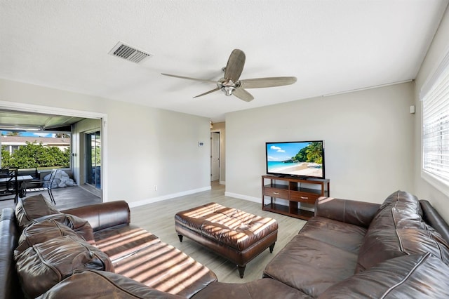 living room featuring ceiling fan, light hardwood / wood-style floors, and a textured ceiling