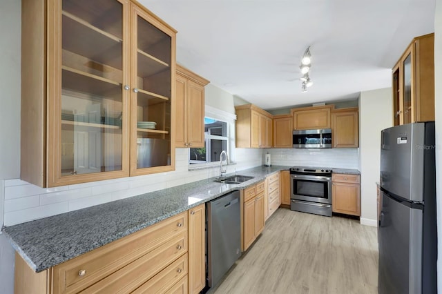 kitchen with sink, stainless steel appliances, light hardwood / wood-style flooring, backsplash, and stone countertops