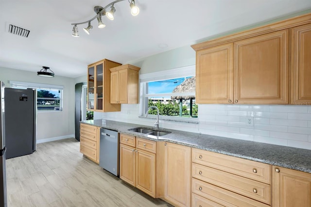 kitchen with appliances with stainless steel finishes, light wood-type flooring, tasteful backsplash, and sink