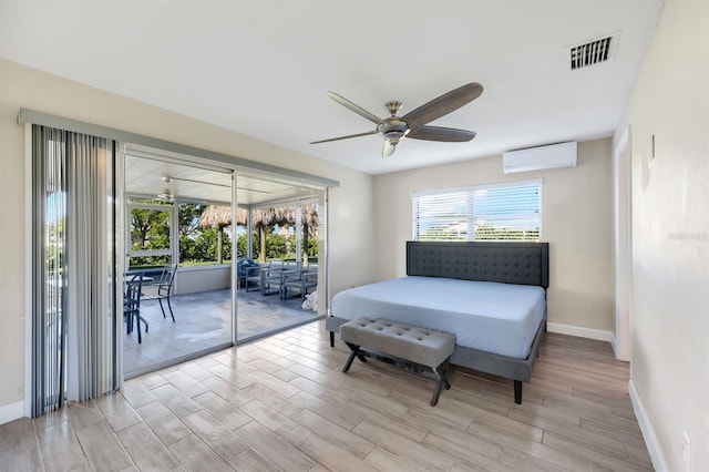 bedroom with access to exterior, light wood-type flooring, a wall unit AC, and ceiling fan