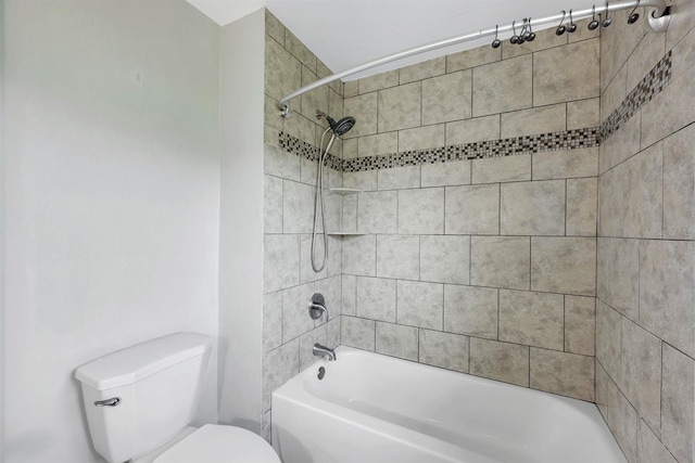 bathroom featuring toilet and tiled shower / bath