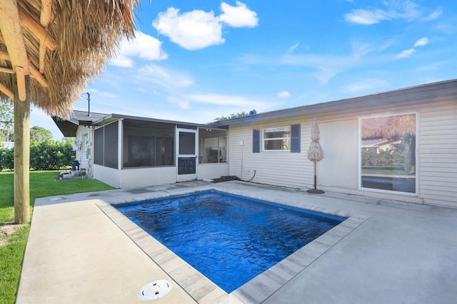 view of pool with a lawn, a patio area, and a sunroom