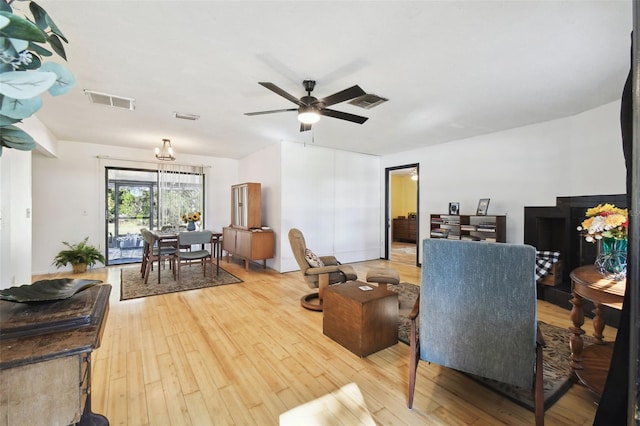 living room featuring ceiling fan with notable chandelier and hardwood / wood-style flooring