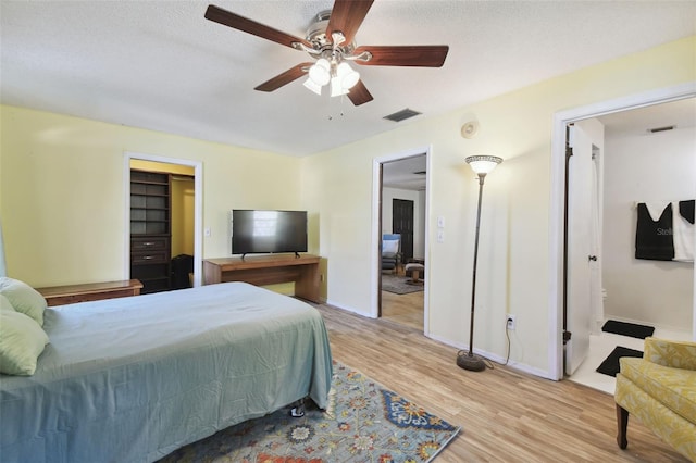 bedroom with ceiling fan, light hardwood / wood-style floors, and a textured ceiling