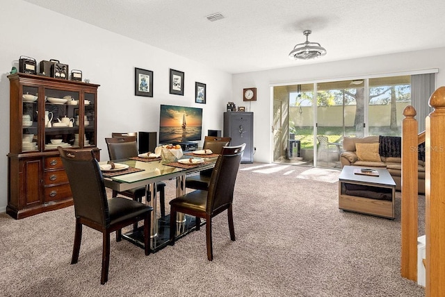 dining room featuring light colored carpet and a textured ceiling