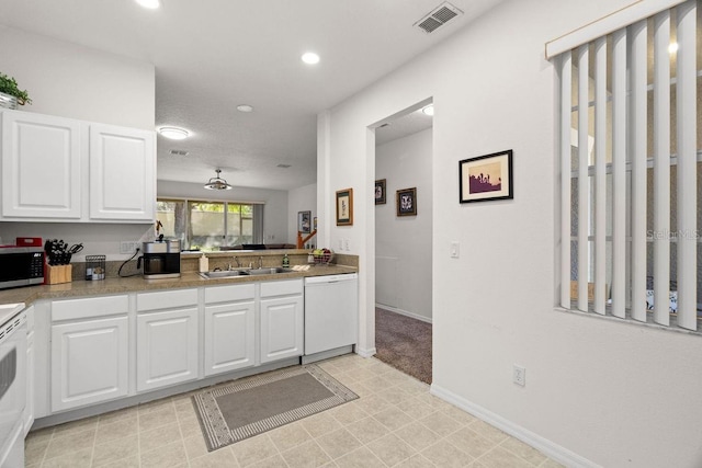 kitchen featuring white dishwasher, ceiling fan, white cabinets, and sink